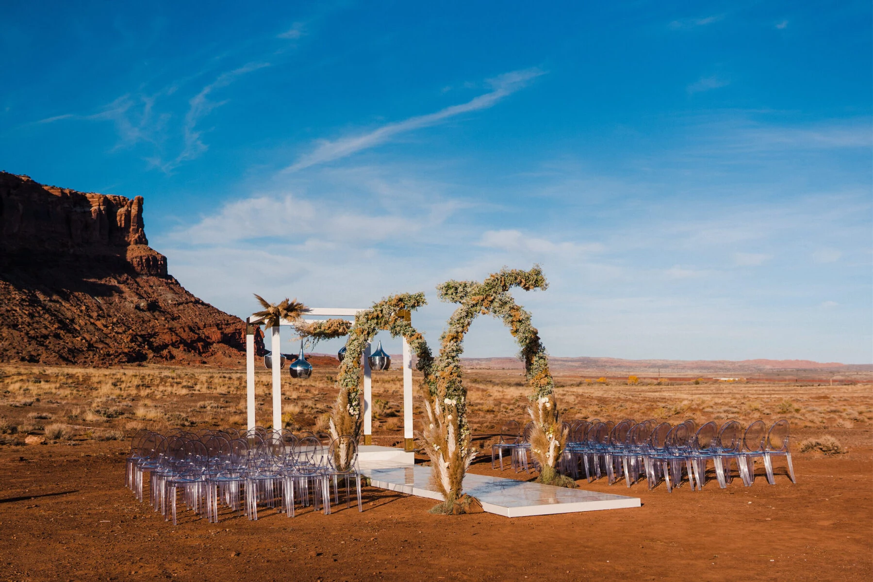 The ceremony at this desert wedding was like a modern oasis—with clear chairs, floral arches, and silver lanterns hanging from the main structure.