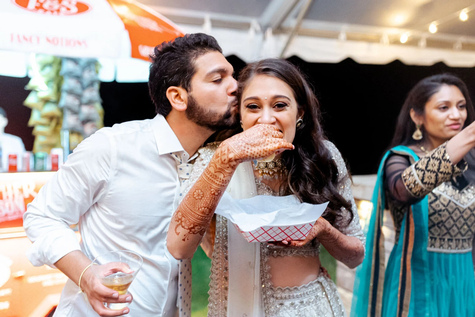 A groom and bride enjoy late-night hot dogs during the reception of their destination Indian wedding.