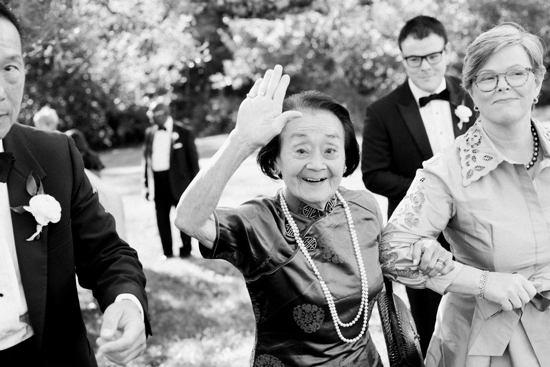 A grandmother waves and smiles following her granddaughter's elevated garden wedding ceremony.