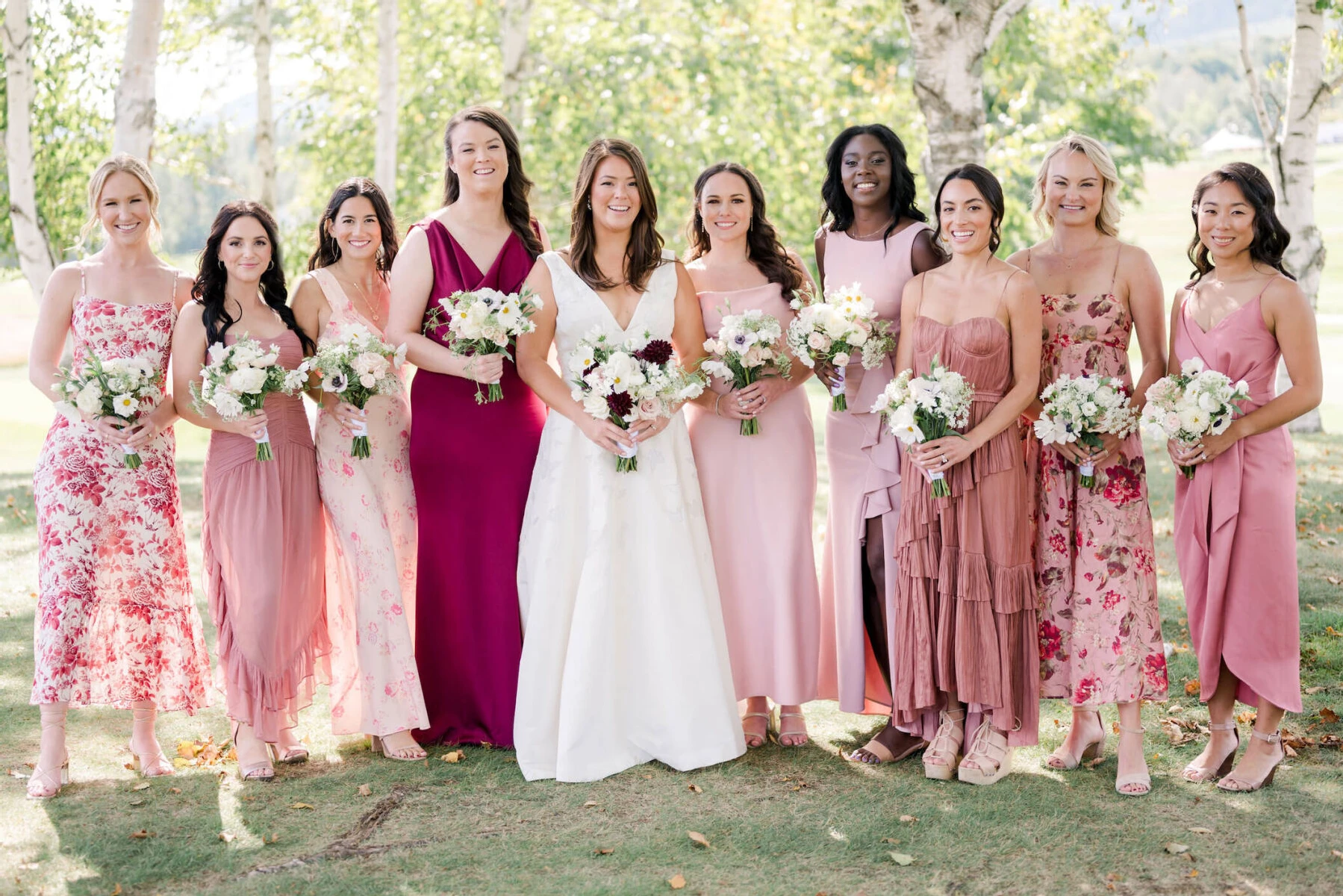 Bridesmaids wore shades of pink and red and carried bouquets of mostly white flowers at an elevated garden wedding in Vermont.