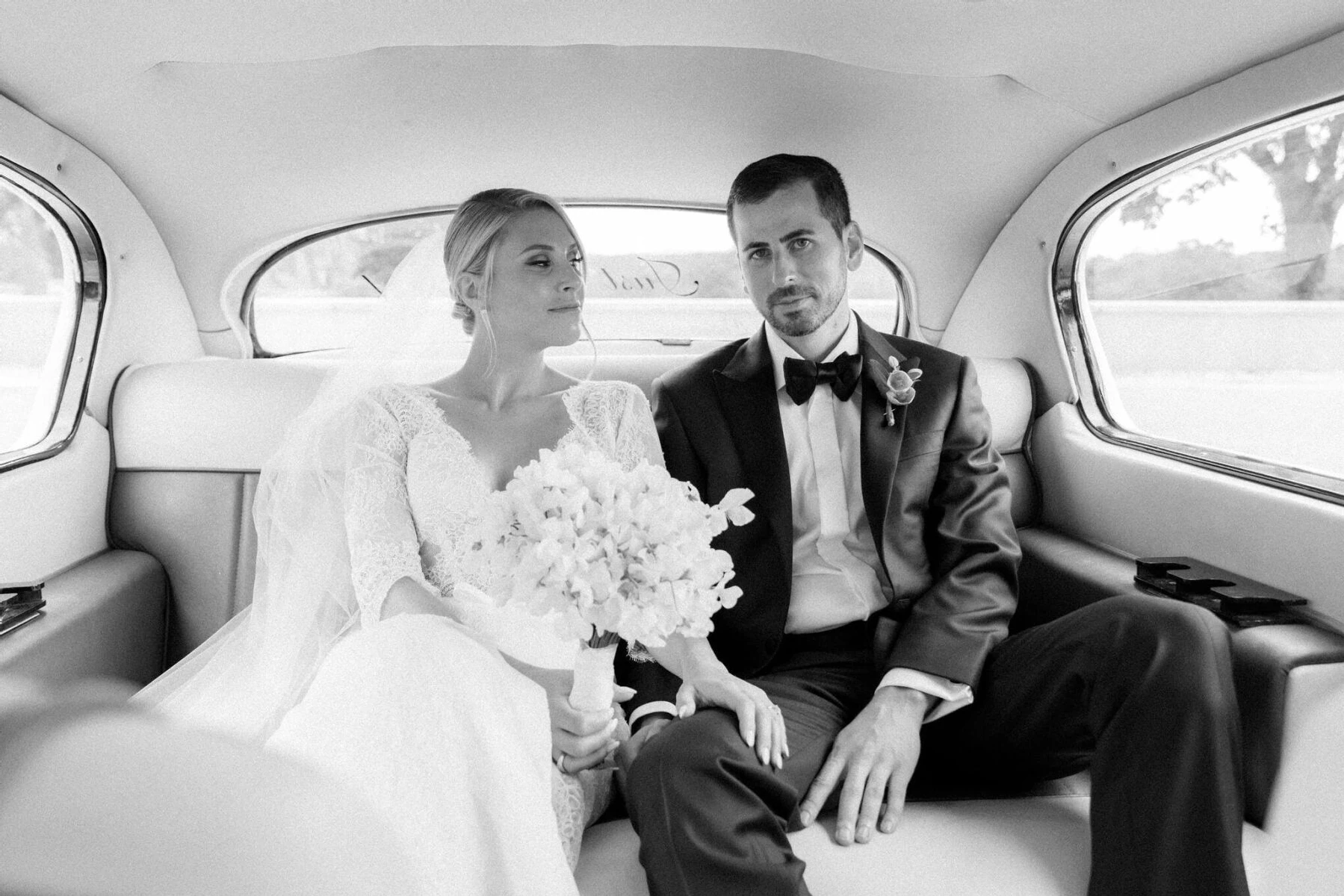 A bride and groom channel Bianca and Mick Jagger while taking pictures inside a vintage Rolls-Royce during their Glenmere Mansion wedding.