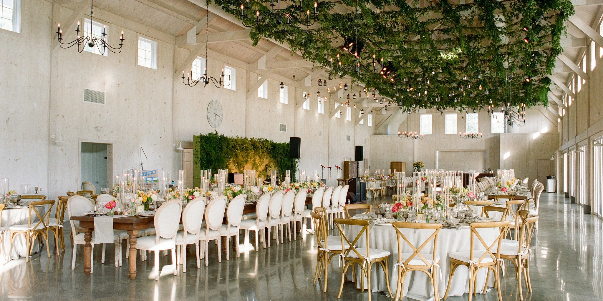 At this Glenmere Mansion wedding, the reception barn was decorated with a lattice of greenery hanging overhead, and a mix of long and round tables decorated with peach and white centerpieces.