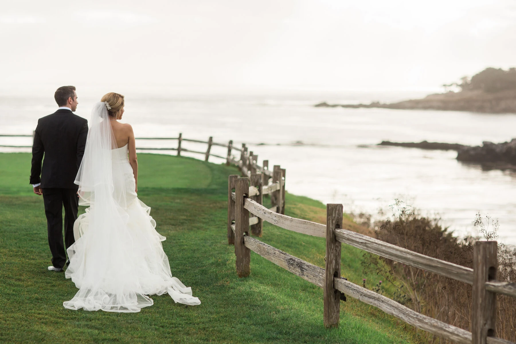 Golf Course Wedding Venues: A wedding couple looks out onto the water from their golf course wedding venue.