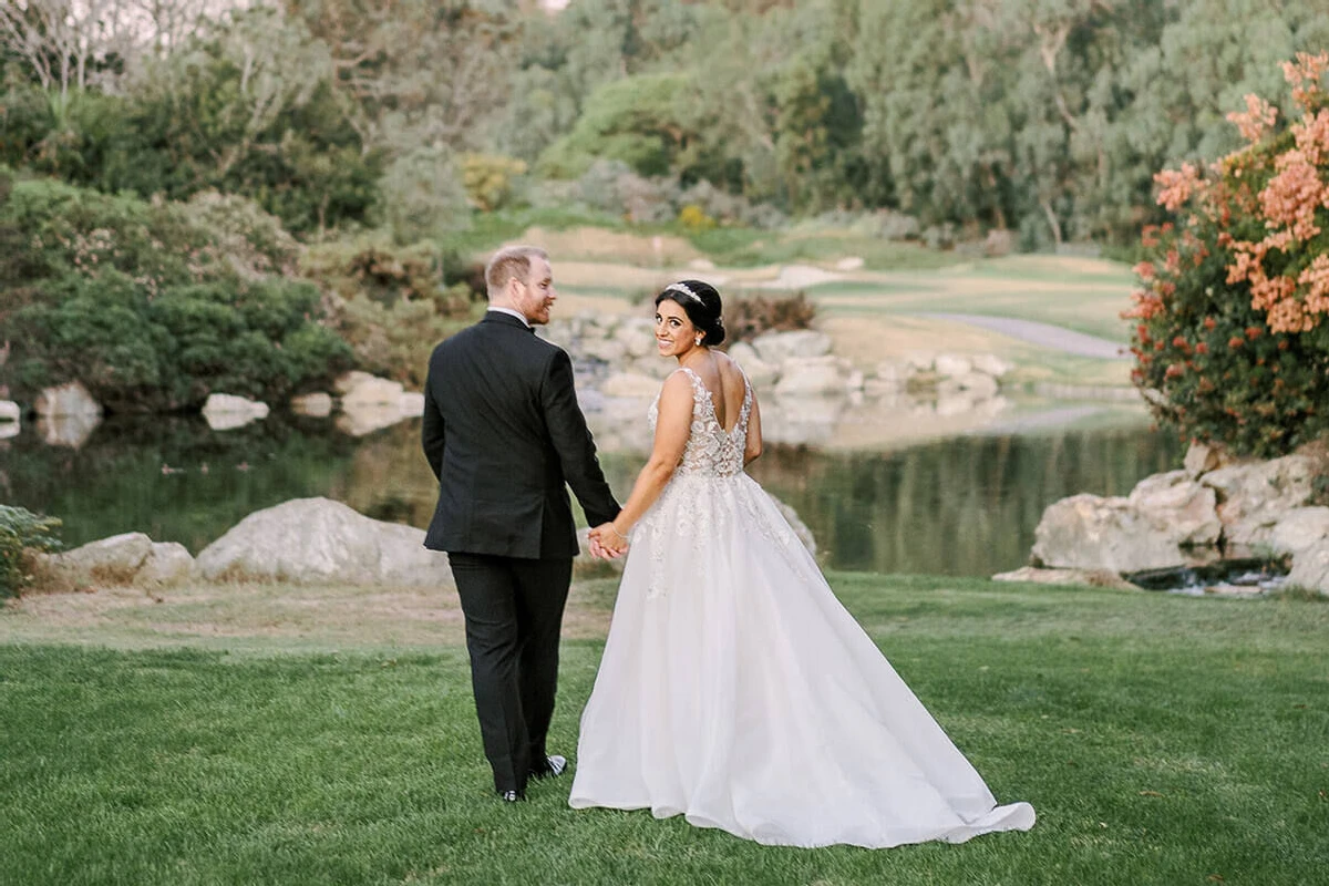 A groom and bride walk the grounds of the Park Hyatt Aviara Resort and pause for portraits by the water.