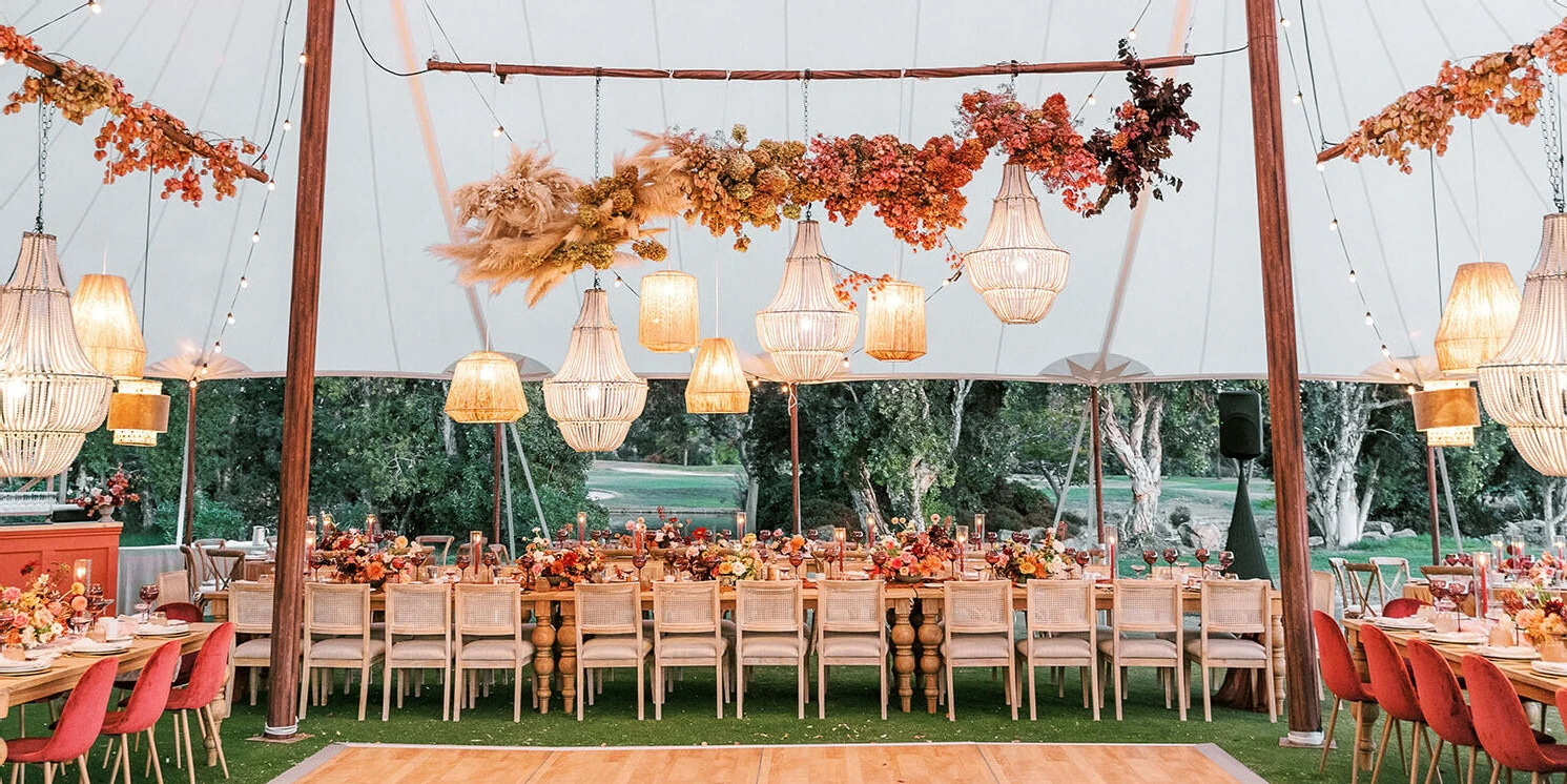 An earth tone wedding reception in a tent in California, all aglow as the sun sets.