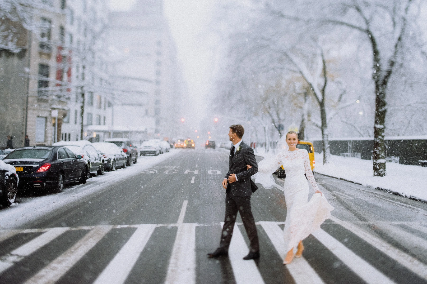 Holiday Wedding: A bride and groom crossing the street during a snowy, winter day.