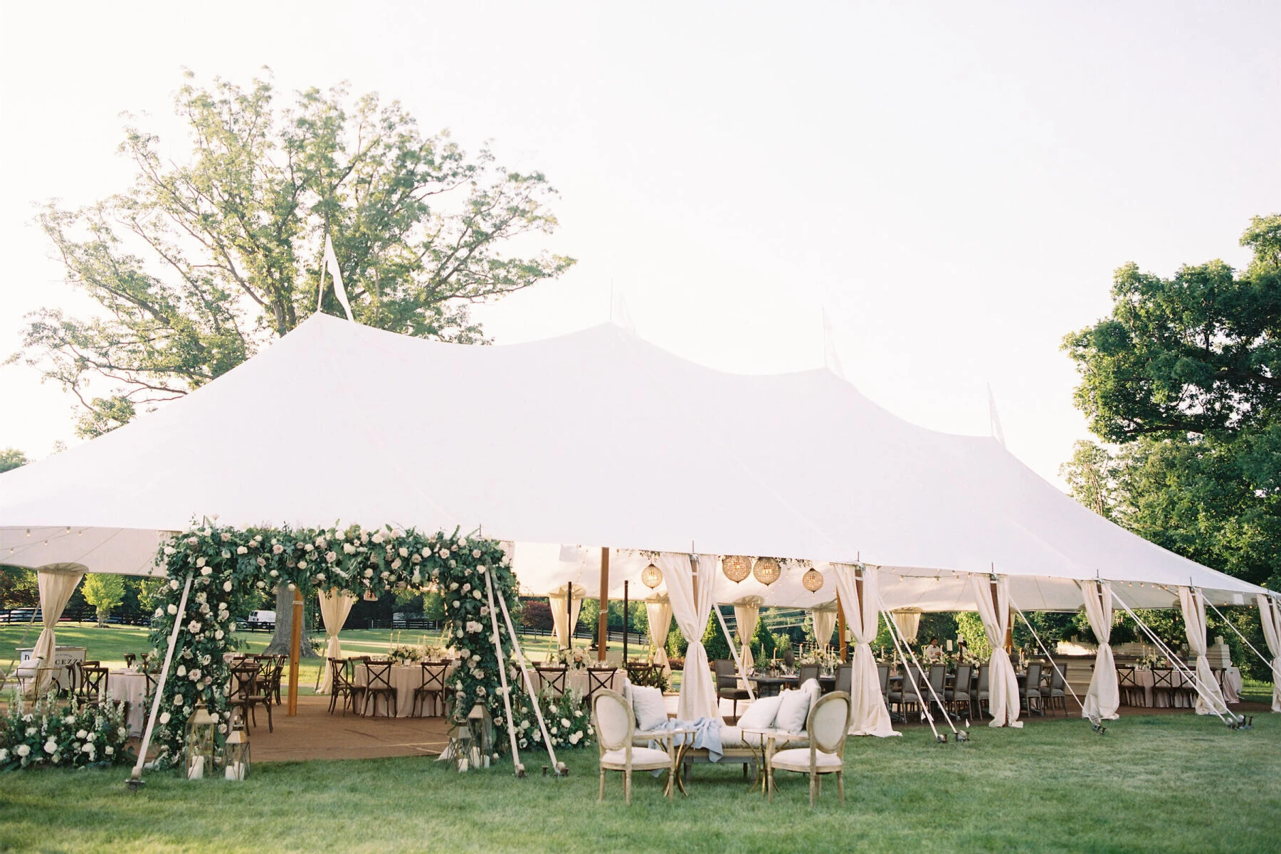 Wedding tent with flower arch around opening.