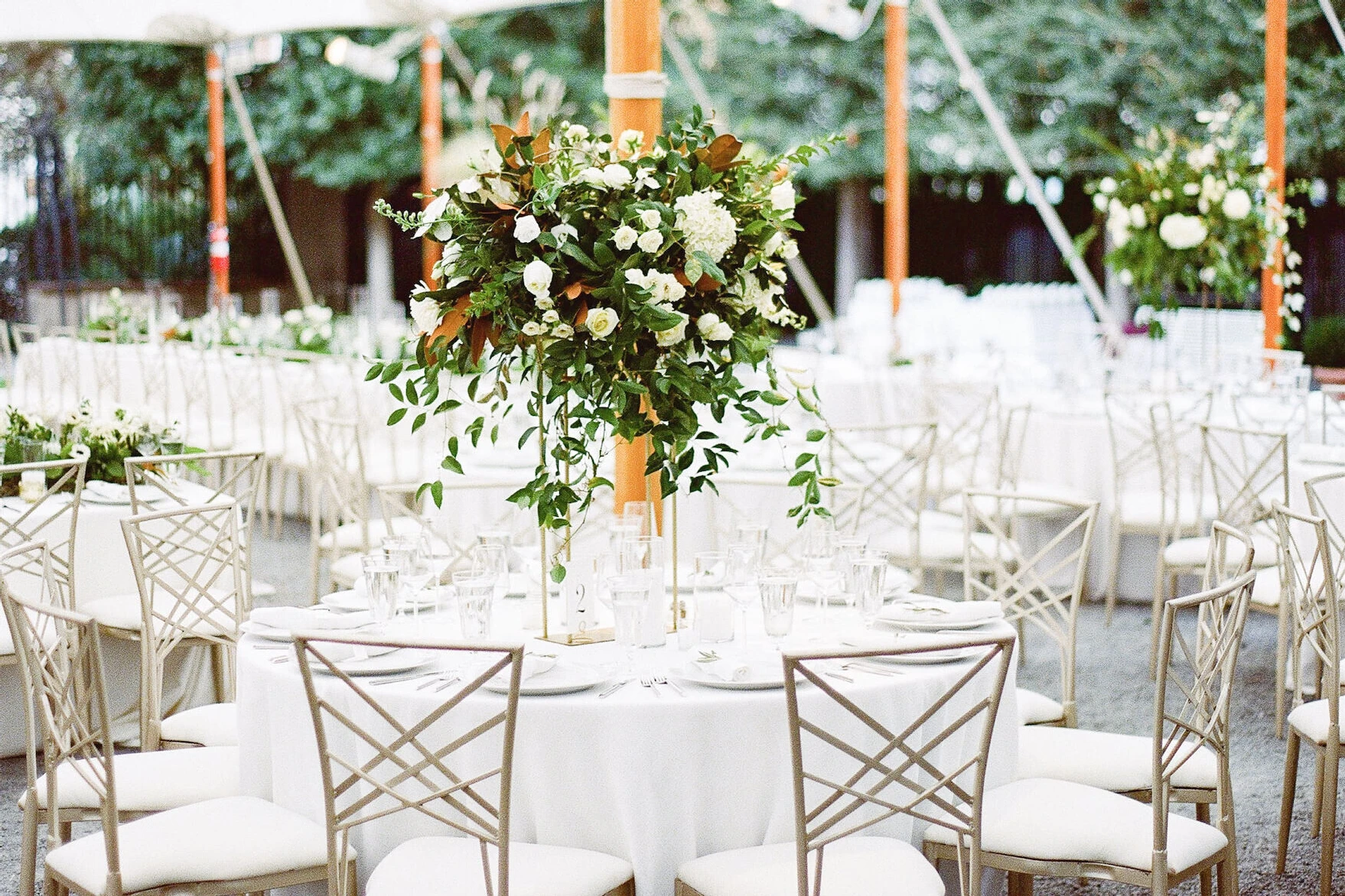 Table underneath a tent at a wedding with flowers in the middle 