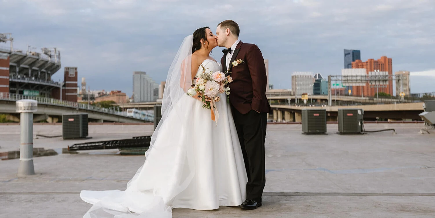 A bride and groom kiss on a rooftop in Baltimore at their industrial wedding.