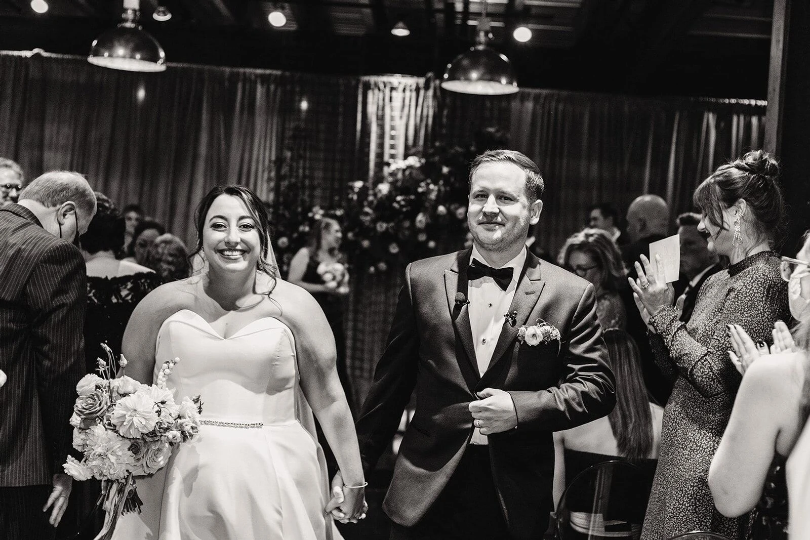 A newlywed couple happily walks up the aisle at the conclusion of their ceremony during their industrial wedding.