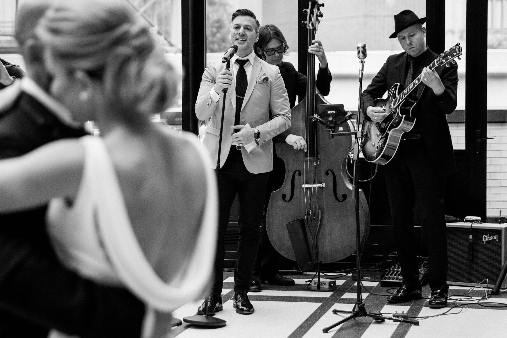 A pair of newlyweds dance as their band performs in the background of their industrial wedding venue.