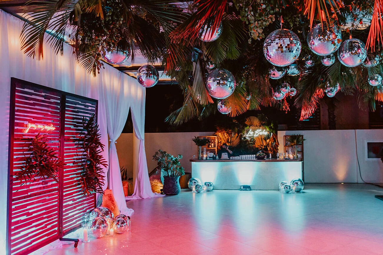 A disco-jungle reception space with a neon sign reading, 