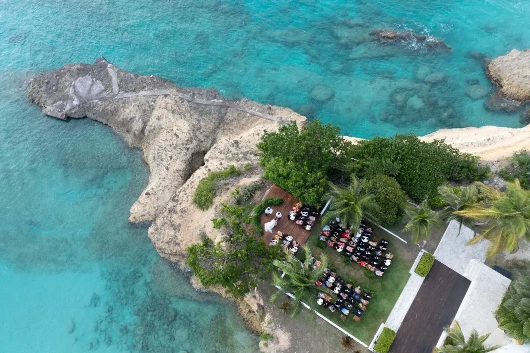 A bird's eye view of an outdoor wedding ceremony on a peninsula property in Anguilla.