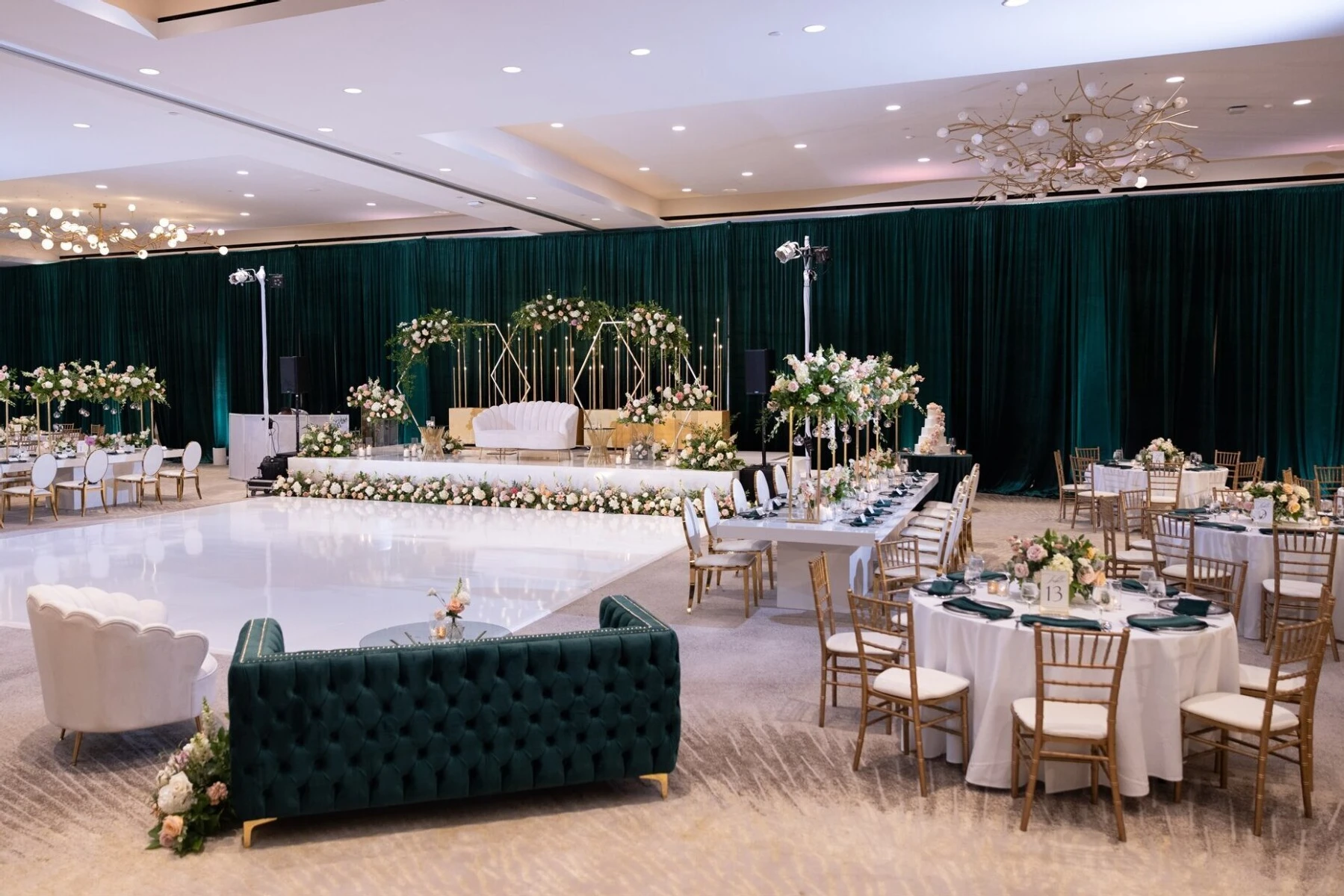 Emerald, gold, and white ballroom wedding reception set up, surrounding a floral-lined white dance floor at The Westin Anaheim Resort in Anaheim, California.