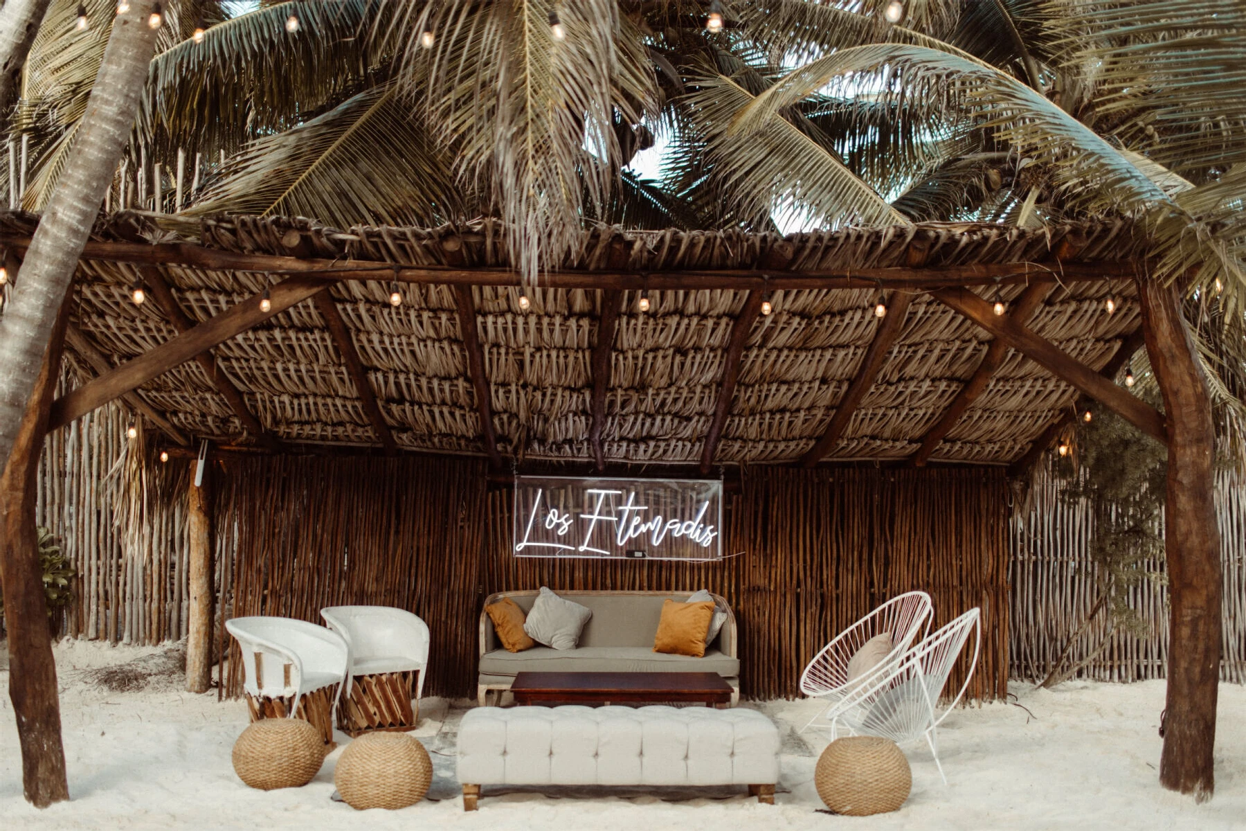 Mexican wedding: neutral modern lounge furniture underneath a straw cabana, featuring a neon sign