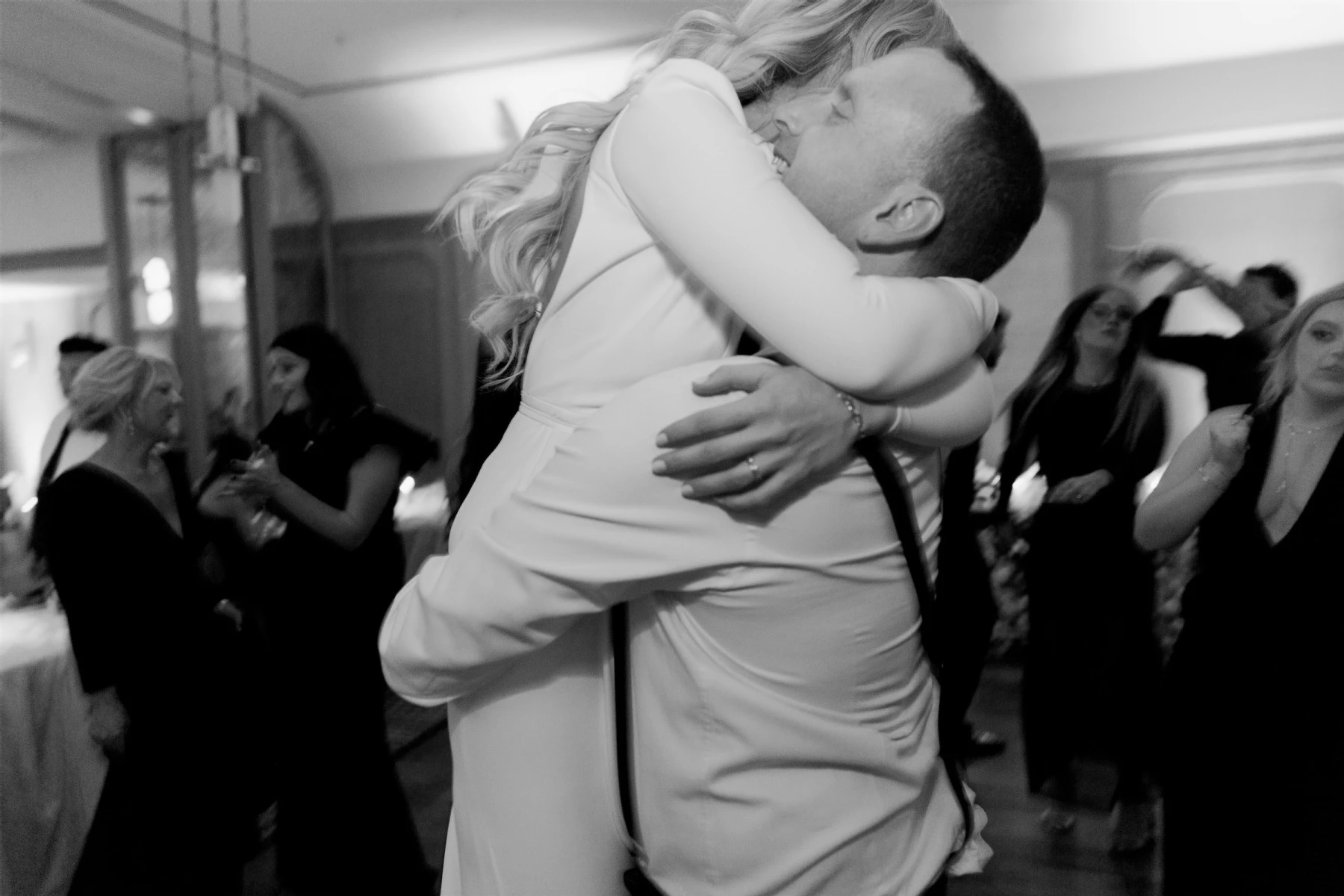 A groom lifts his bride up on the dance floor in the ballroom where their modern California wedding reception took place.