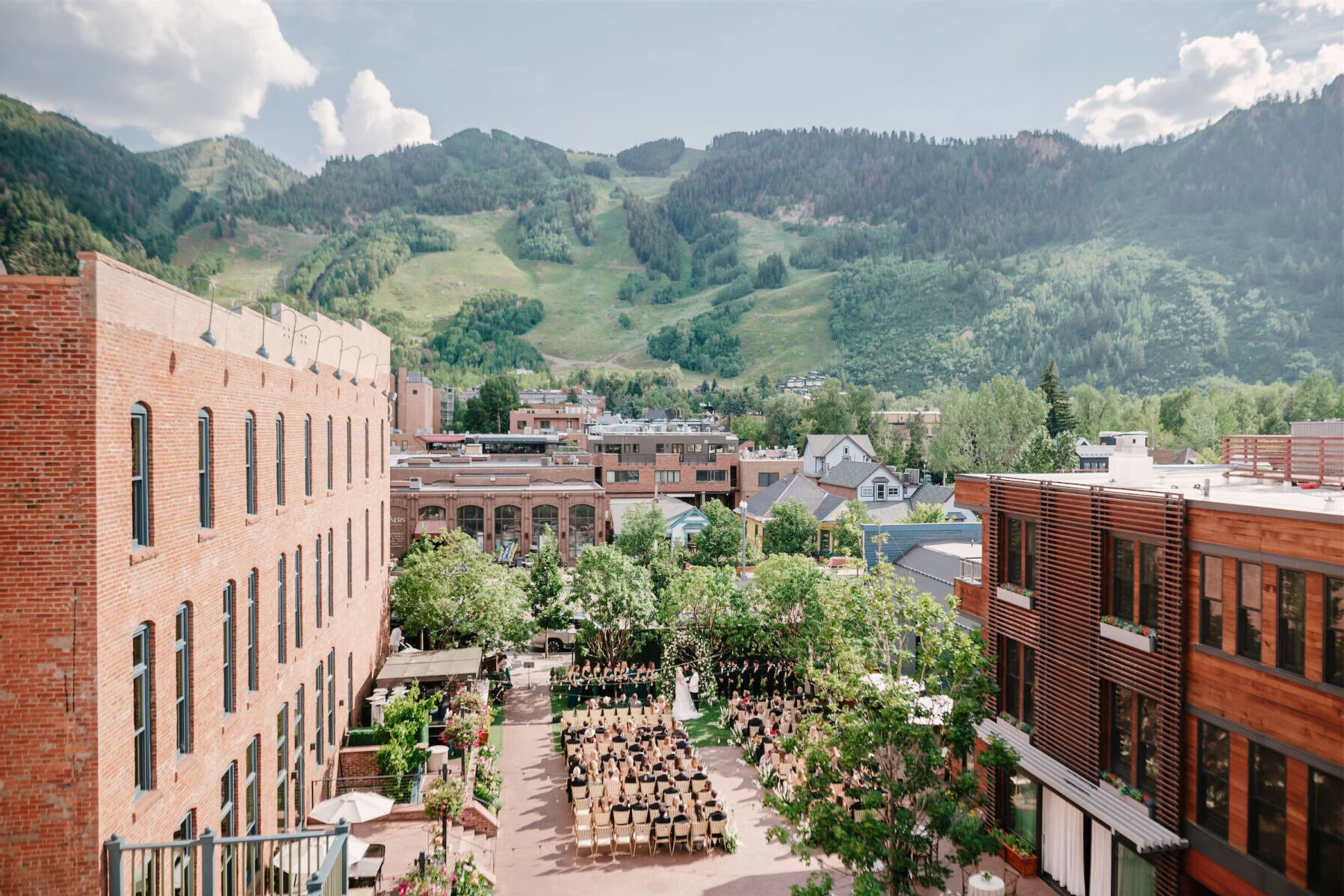 Mountain wedding details: 
Aerial shot of the courtyard of Hotel Jerome, hosting a green-and-white wedding ceremony with views of the mountains in the distance.