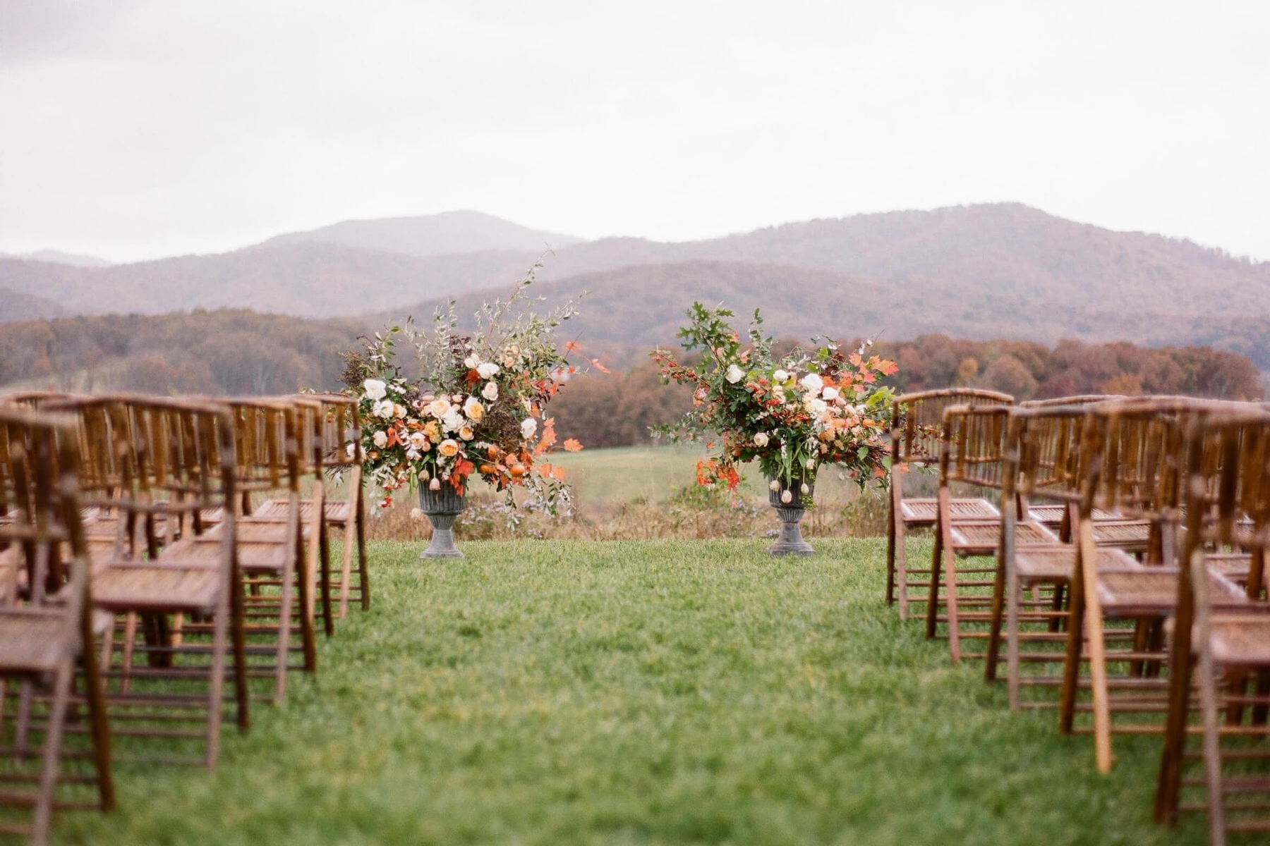 Pippin Hill Farm: A ceremony setup with wooden chairs and two bouquets overlooking rolling hills in Virginia.