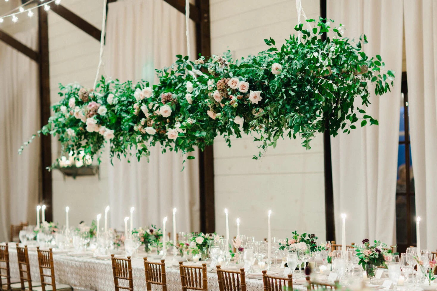 Pippin Hill Farm: A hanging floral installation with greenery and pink flowers in an indoor reception area at Pippin Hill in Virginia.