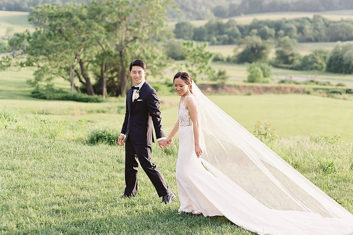 Pippin Hill Farm: A wedding couple walking while holding hands on a hill in Virginia.