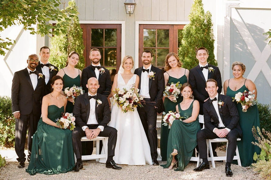 Pippin Hill Farm: A bridal party in tuxedos and emerald green dresses posing for a portrait with a bride and groom.