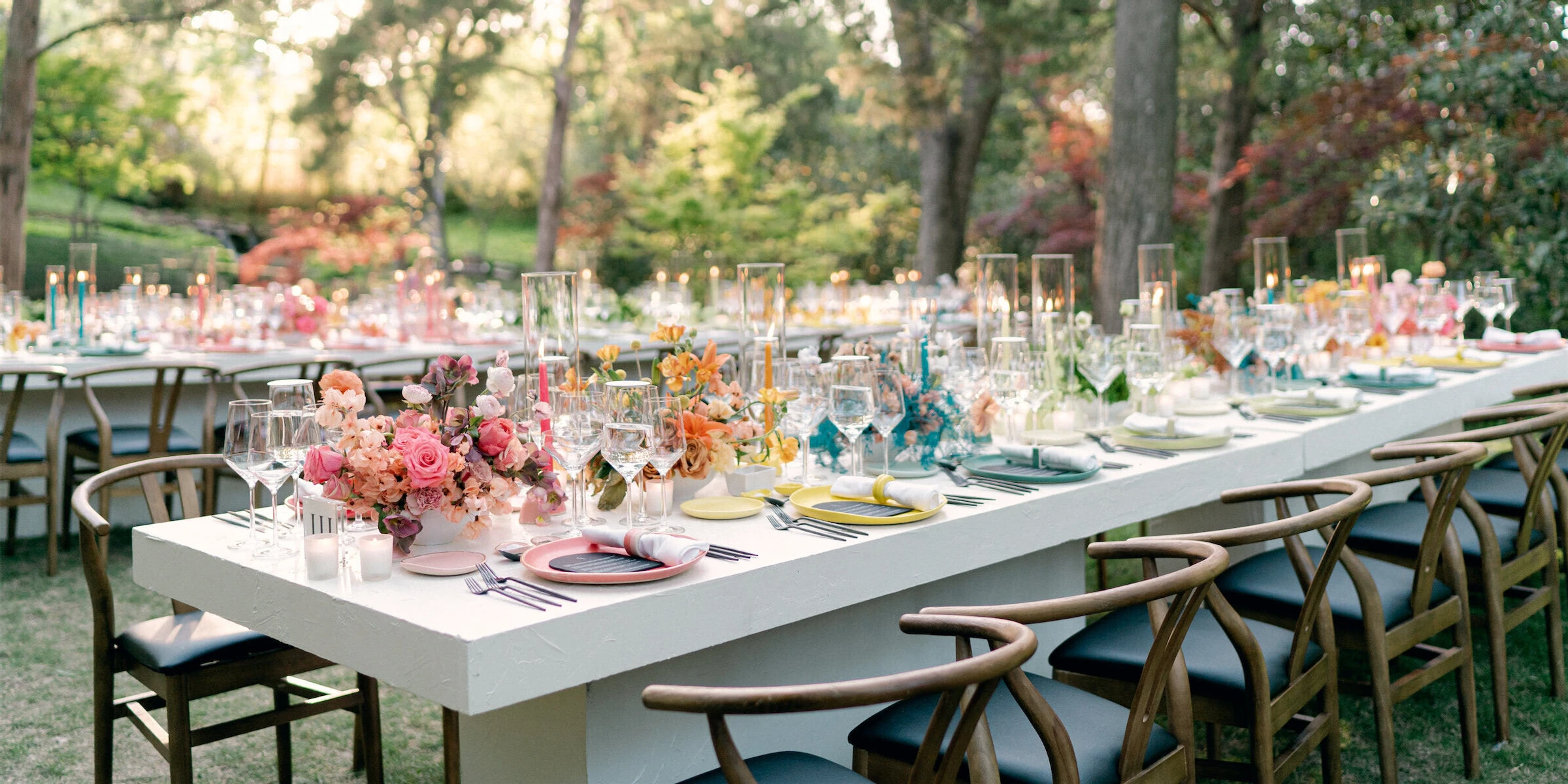 A rainbow wedding reception with long tables showcasing colorful placesettings and floral centerpieces.