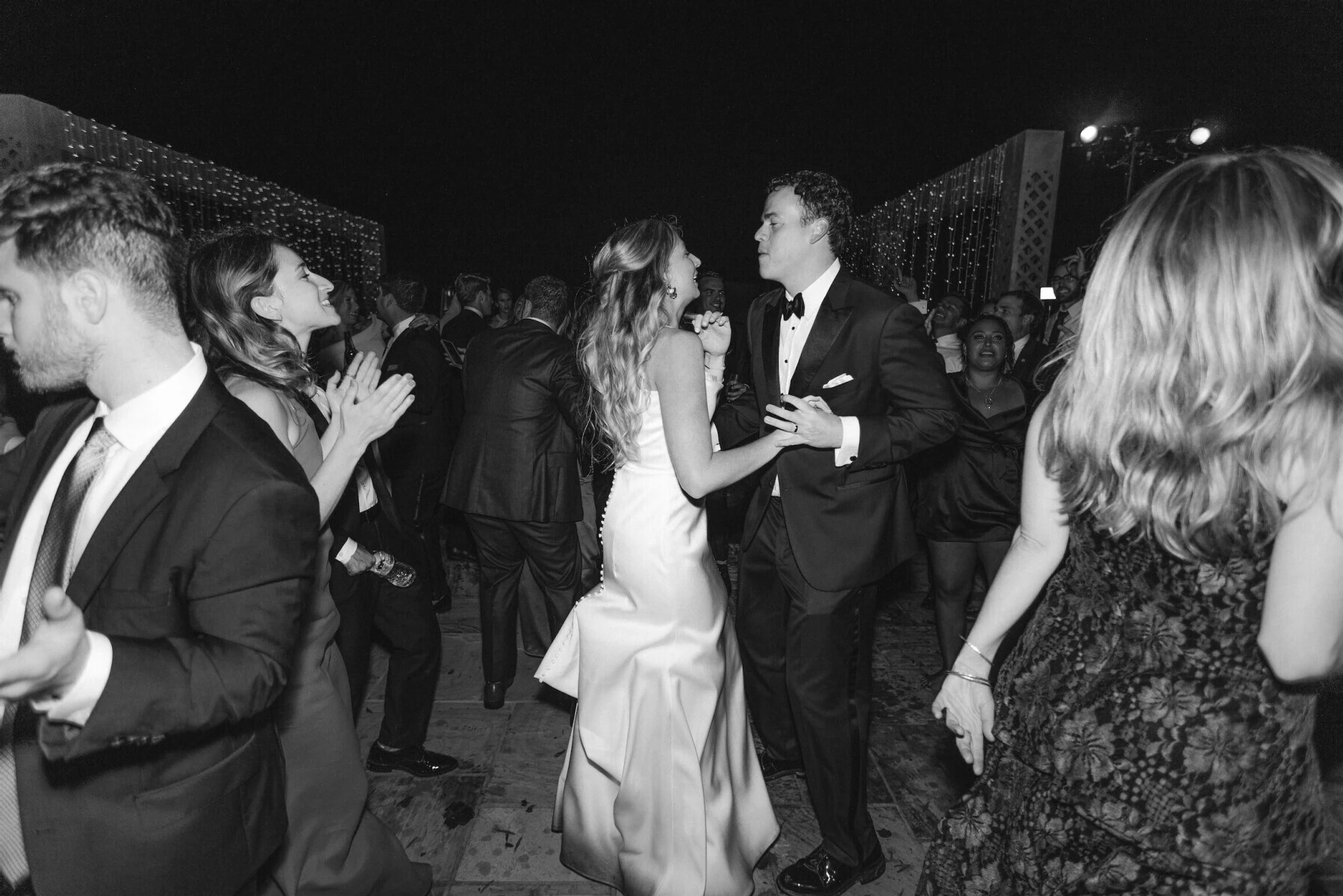 Newlyweds and their guests dance at the reception of a rustic outdoor wedding.