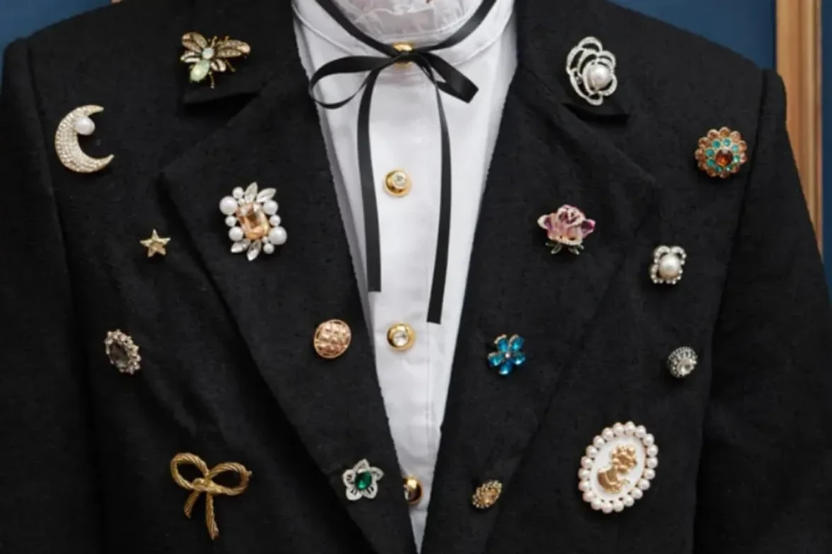 Black jacket with a ruffled white collar and a black ribbon tie, shot close. 
