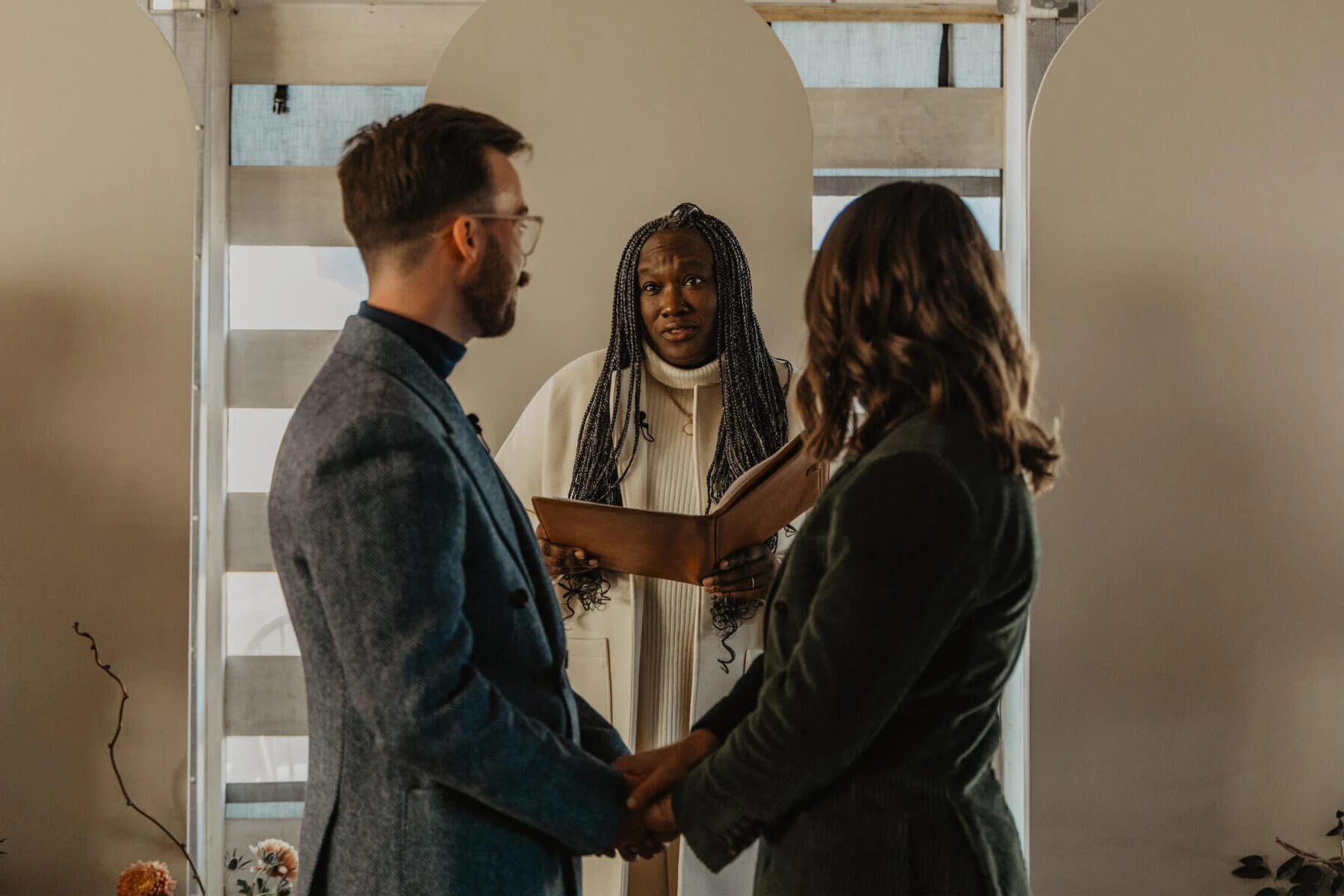 A couple glances at their officiant during their indoor wedding ceremony.