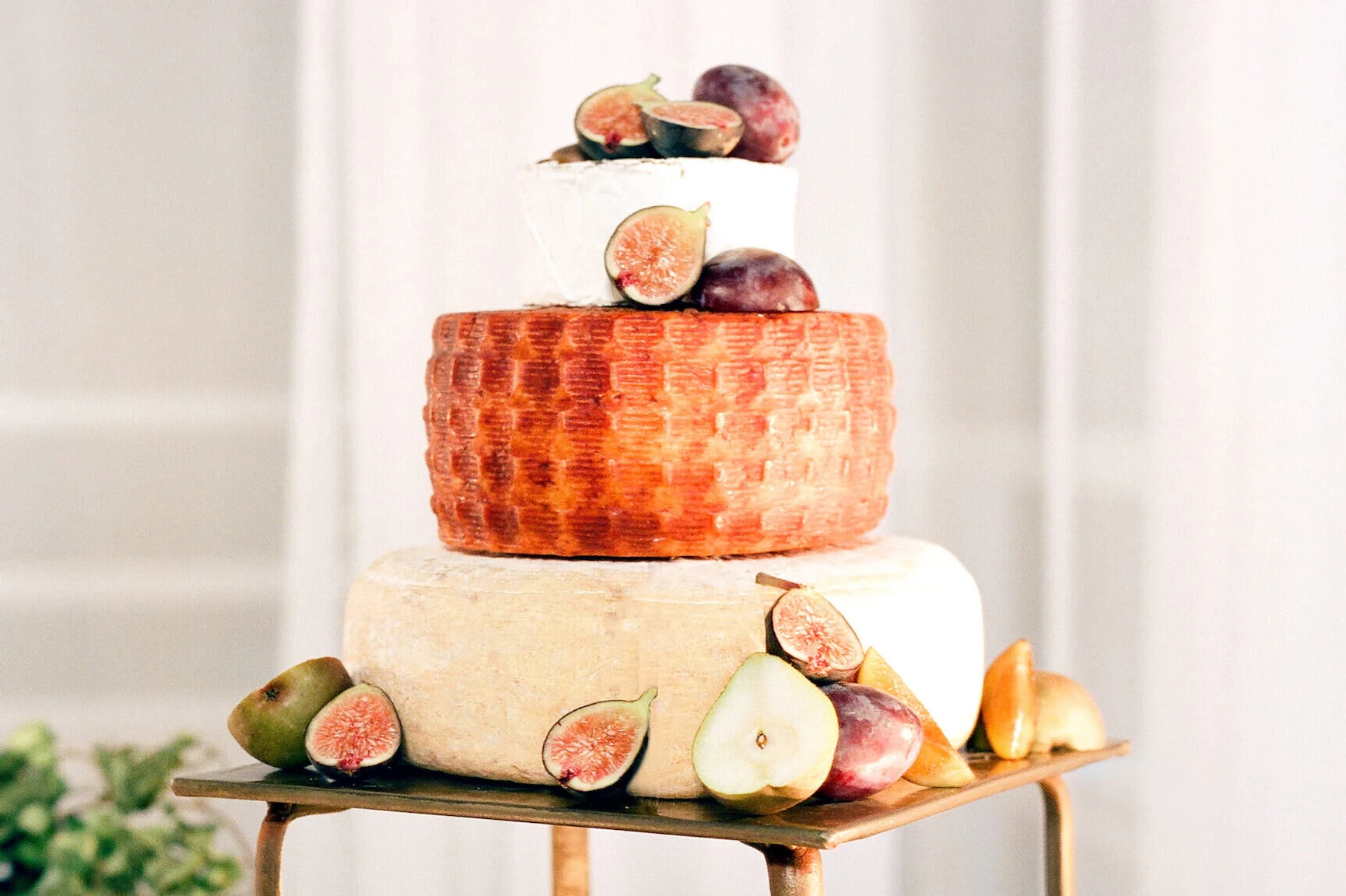 Wedding cake bakery: tiered wedding cake made of giant cheese wheels topped with figs. 