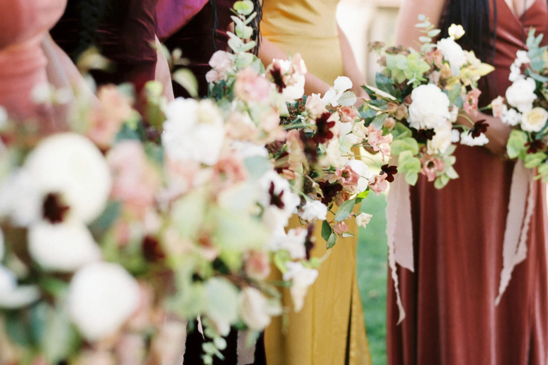 Wedding details: Bridesmaids bouquets against colorful velvet dresses.