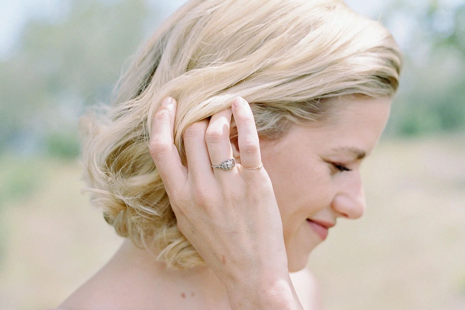 Pink wedding details: A bride tucks her slightly wavy hair behind her ear.