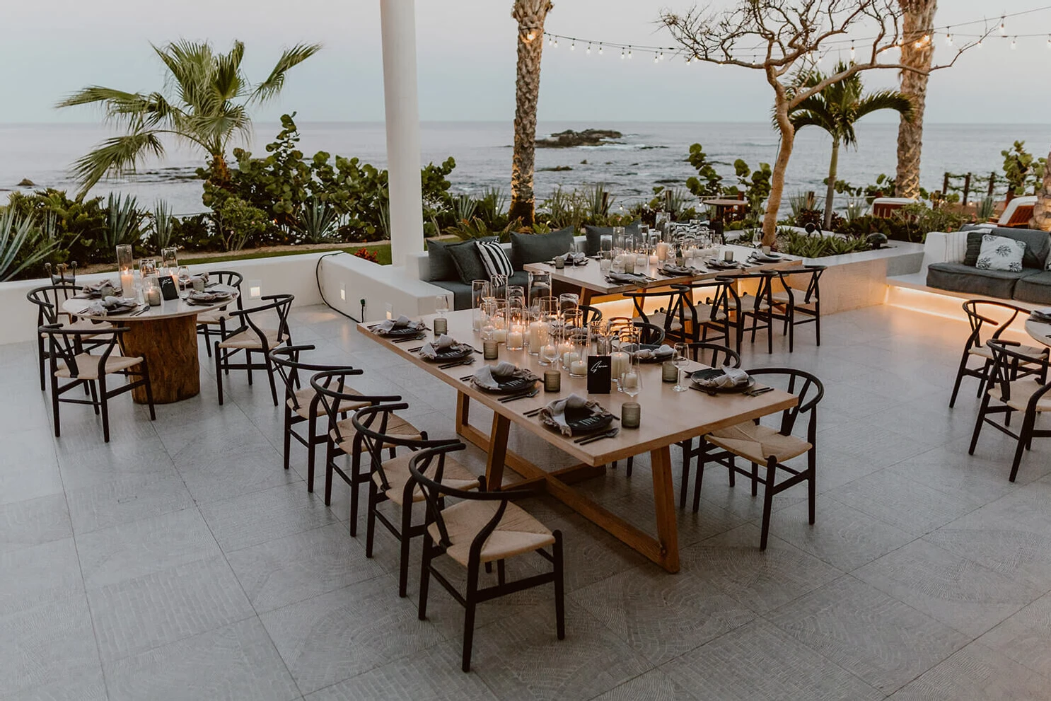 An outdoor Cabo wedding reception at Comal (the restaurant of Chileno Bay Resort) included wood tables, black chairs and tabletop pieces, and plenty of candlelight.