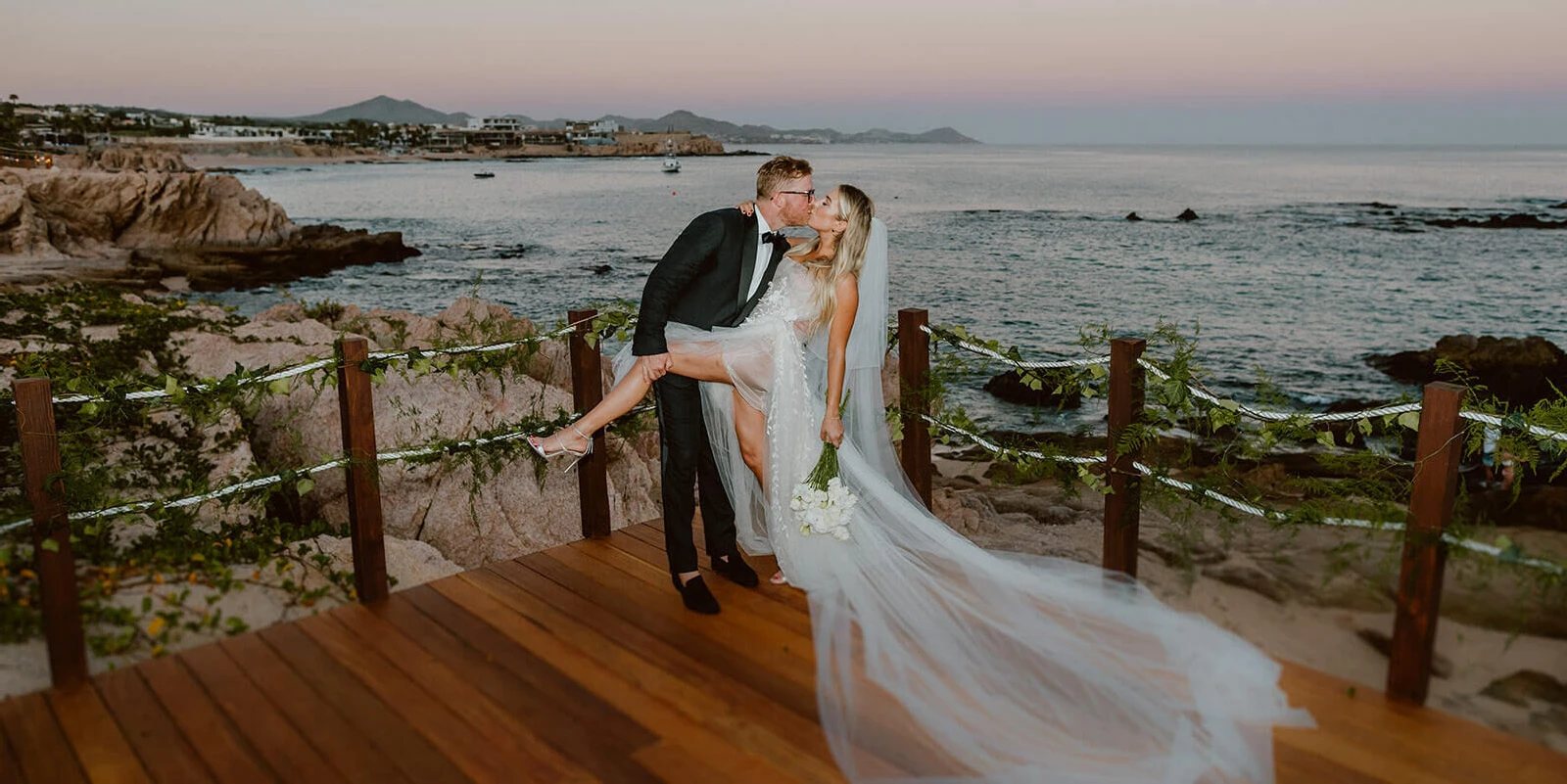 A groom dips his bride during a post-ceremony portrait at their beachfront Cabo wedding.